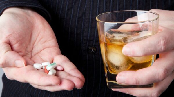 copo com bebida alcoólica ao lado de comprimidos sobre a mesa