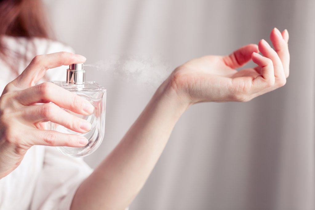 Mulher passando perfume no pulso